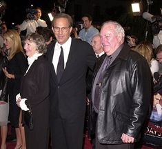 three people standing next to each other on a red carpet at an event with cameras around them