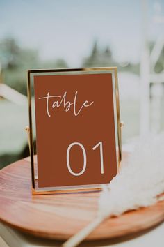 a table with a sign that says table 01 on it and some feathers in the background