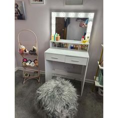 a white vanity table with a mirror and stool in a small room next to a wall