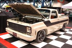 an old pickup truck with its hood open on display at a car show in a building