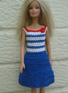 a doll wearing a blue and white crochet dress with red flower on the top