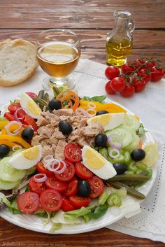 a large salad on a plate with olives, tomatoes, lettuce and cheese