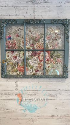 an old window is decorated with flowers and seashells on the side of a wall