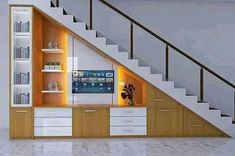 an entertainment center under the stairs with built in shelving unit and television on it