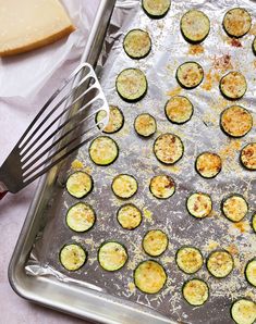 zucchini on a baking sheet with a spatula next to it and cheese