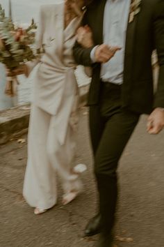 a man in a suit and tie walking next to a woman wearing a white dress