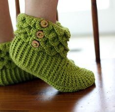 a close up of a person's feet wearing green knitted slippers with buttons