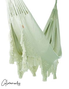 a white hammock with tassels hanging from it's back end