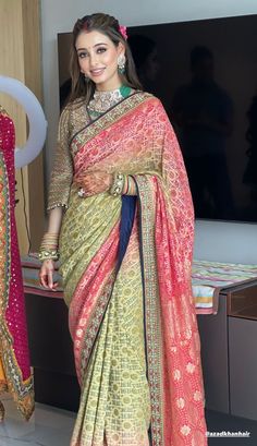 a woman in a sari standing next to a tv