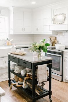 a kitchen island with plates and cups on it in the middle of a wooden floor