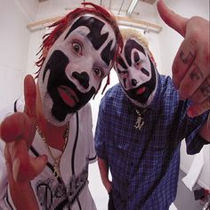 two men with painted faces are pointing at the camera