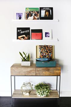 there is a shelf with some books on it and pictures hanging above the shelves in this room