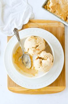 two scoops of ice cream sit in a bowl on top of a cutting board