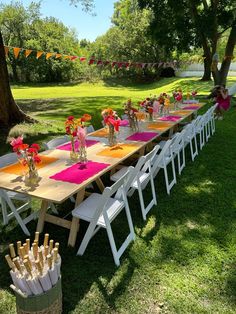 a long table set up with pink and yellow napkins on it for a party