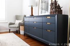 a large blue dresser sitting in the corner of a room next to a chair and lamp