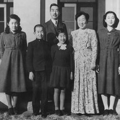 an old black and white photo of people standing in front of a building with two children