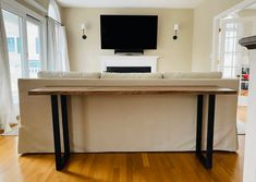 a living room with wood floors and a tv mounted on the wall above a couch