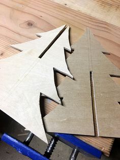 cut out pieces of cardboard to make a wooden christmas tree ornament on a workbench