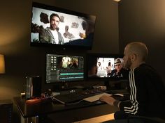 a man sitting at a desk in front of two computer monitors with the same image on them