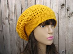 a female mannequin head wearing a yellow knitted beanie on top of a wooden surface