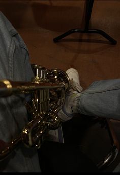 the legs of a person sitting on a chair with a brass instrument in their lap