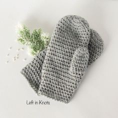 a knitted mitten next to a plant on a white surface with the words left in knots written below it