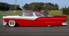 an old red and white car parked in a parking lot