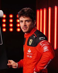 a man in a red racing suit holding up a laptop