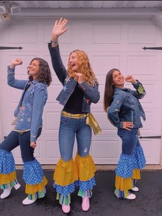 three women dressed in blue and yellow are posing for the camera with their hands up