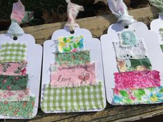 four tags with different designs on them hanging from clothes pins