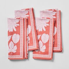 four napkins with leaves on them are folded in pink and white colors, sitting next to each other