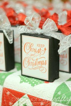 three small black boxes with red bows on them sitting on top of a quilted tablecloth