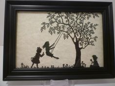 a shadow of two children swinging on a tree