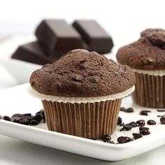 three chocolate muffins on a plate with coffee beans