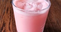 a pink drink sitting on top of a wooden table