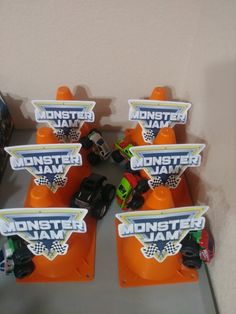 some toy cars sitting on top of an orange stand in front of a white wall