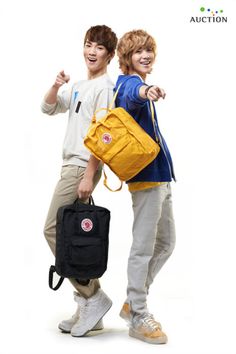 two young men standing next to each other with backpacks on their backs and one holding a bag