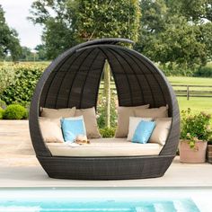 an outdoor day bed next to a swimming pool with pillows on the back and side