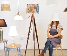 a woman sitting on a chair in front of lamps