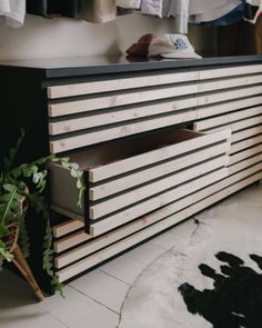 a black and white dresser sitting on top of a floor next to a potted plant