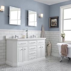 a bathroom with blue walls and white tile on the floor, two mirrors above the bathtub