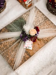 a bouquet of flowers sits on top of a glass box with ribbon around the edges