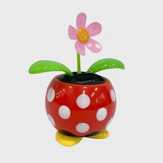 a red and white polka dot pot with a pink flower in it