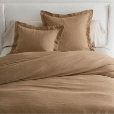 an unmade bed with brown linens and pillows