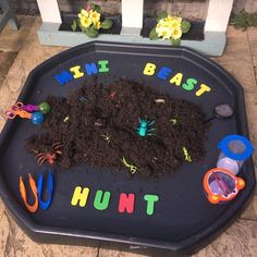 a child's play tray filled with dirt and gardening utensils