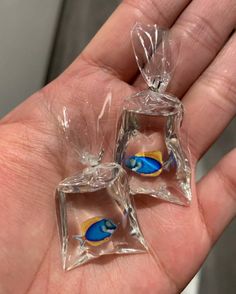 two pieces of clear glass with blue and yellow designs on them are being held in someone's hand