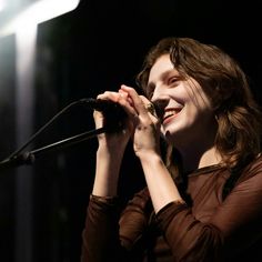 a woman singing into a microphone on stage