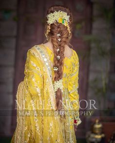 a woman with long hair wearing a yellow dress and braid in her hair, standing outside