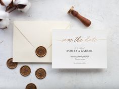 a wedding save the date card and wax stamp on top of a white envelope next to some cotton