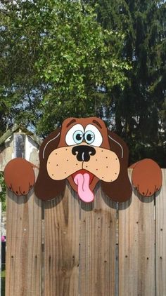 a wooden fence with a cartoon dog on it's face and tongue sticking out